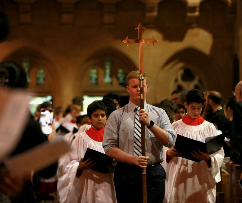 Student walking down the corridor of Church holding a cross